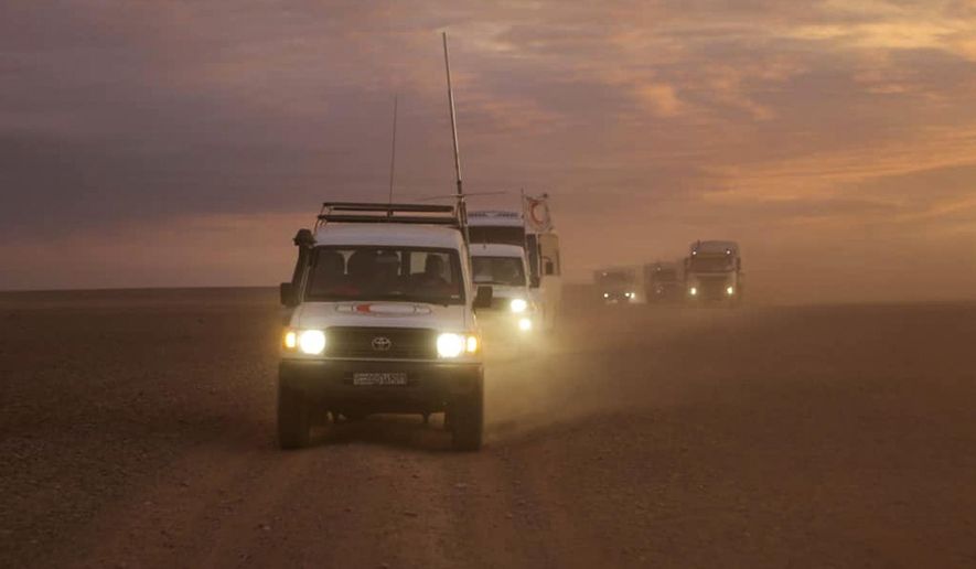 This photo released by the Syrian Arab Red Crescent, shows a convoy of vehicles of the Syrian Arab Red Crescent driving in the Syrian desert heading to Rukban camp between the Jordan and Syria borders, Sunday, Nov. 4, 2018. U.N. officials and volunteers from the Syrian Arab Red Crescent offered vaccinations for children Sunday and distributed much needed aid, the first such assistance since January to reach thousands of people in a remote camp for the displaced on Syria's border with Jordan. Residents say it is the first time they see international humanitarians roaming their desolate camp, where nearly 50,000 have been stranded in a political void. (Syrian Arab Red Crescent via AP)