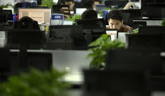 In this Oct. 31, 2018, photo, a Watrix employee works at his desk in their company&#39;s offices in Beijing. A Chinese technology startup hopes to begin selling software that recognizes people by their body shape and how they walk, enabling identification when faces are hidden from cameras. Already used by police on the streets of Beijing and Shanghai, “gait recognition” is part of a major push to develop artificial-intelligence and data-driven surveillance across China, raising concern about how far the technology will go. (AP Photo/Mark Schiefelbein) **FILE**