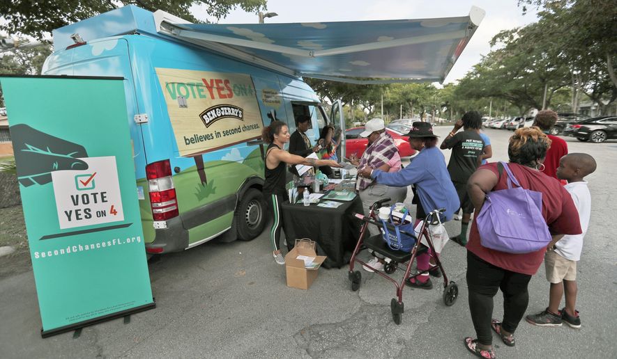 In this, Monday, Oct. 22, 2018 photo, people gather around the Ben & Jerry's "Yes on 4" truck as they learn about Amendment 4 and eat free ice cream at Charles Hadley Park in Miami. Amendment 4, asks voters to restore the voting rights of people with past felony convictions. More than 1.5 million adults in Florida are ineligible to vote because they have felony convictions. (AP Photo/Wilfredo Lee)