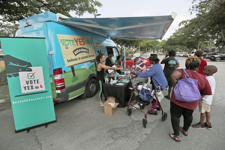 In this, Monday, Oct. 22, 2018 photo, people gather around the Ben & Jerry's "Yes on 4" truck as they learn about Amendment 4 and eat free ice cream at Charles Hadley Park in Miami. Amendment 4, asks voters to restore the voting rights of people with past felony convictions. More than 1.5 million adults in Florida are ineligible to vote because they have felony convictions. (AP Photo/Wilfredo Lee)