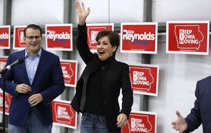 Iowa Gov. Kim Reynolds waves to supporters before speaking at a campaign rally, Monday, Nov. 5, 2018, in Ankeny, Iowa. Iowa acting Lt. Gov. Adam Gregg, left, looks on. (AP Photo/Charlie Neibergall)