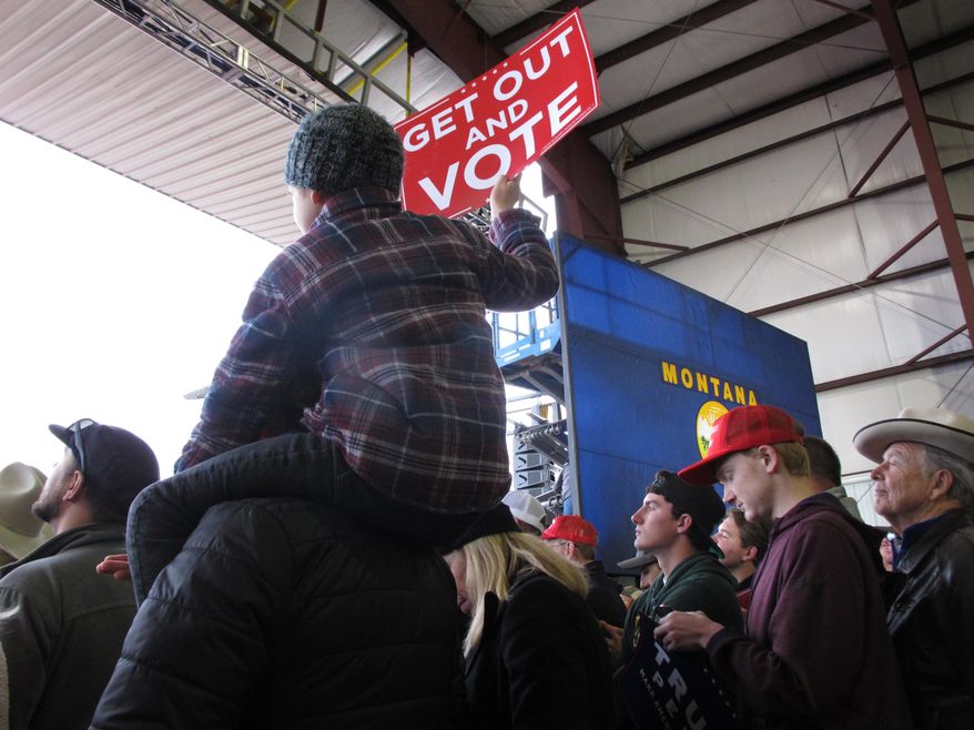 In this Nov. 3, 2018 photo a boy holds a sign during a rally with President Donald Trump in Belgrade, Mont. Vice President Mike Pence is headlining a Montana rally for State Auditor Matt Rosendale on Monday, Nov. 5, 2018, as the Republican's bid to unseat Democratic incumbent Sen. Jon Tester barrels toward its conclusion. (AP Photo/Matt Volz)