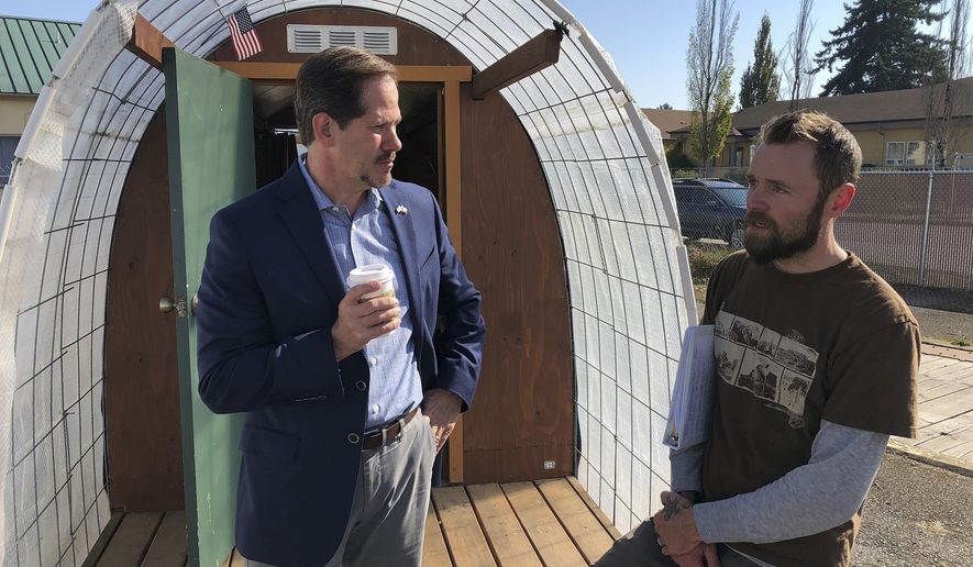 FILE- In this Oct. 22, 2018, file photo, Oregon Rep. and Republican gubernatorial candidate Knute Buehler, left, speaks with Erik De Buhr, co-executive director of Community Supported Shelters in front of a hut for homeless veterans, in Eugene, Ore. Democrats have occupied the Oregon governor's mansion since 1987. But in this election, Gov. Kate Brown faces a challenge from Buehler, a state lawmaker who describes himself as a moderate and is competitive. (AP Photo/Andrew Selsky, File)