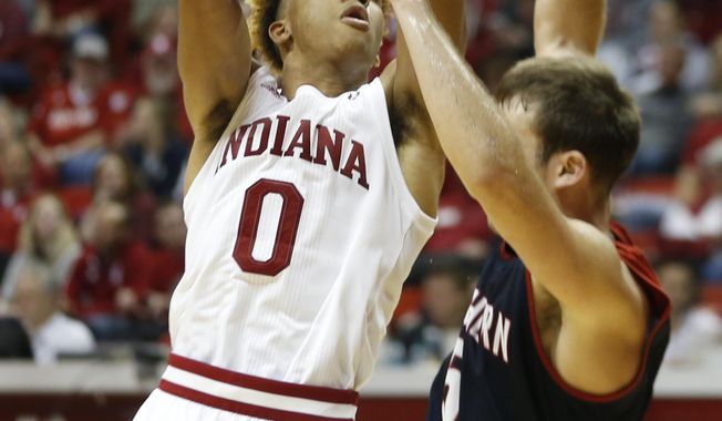 FILE - In this Nov. 1, 2018 file photo, Indiana&#x27;s Romeo Langford (0) shoots as Southern Indiana&#x27;s Nate Hansen (5) defends during a college basketball exhibition game, in Bloomington, Ind. Indiana Hoosiers fans spent years envisioning Langford in a crimson-and-cream uniform and those trademark candy-striped warmup pants. They treated him like Damon Bailey, Jared Jeffries, Eric Gordon, Cody Zeller and Kevin “Yogi” Ferrell by searching recruiting boards for hints about his future college destination. They hoped he would hang a sixth national championship banner at Assembly Hall. Their long wait finally ends Tuesday night when Indiana hosts Chicago State.  (Jeremy Hogan /The Herald-Times via AP, File)