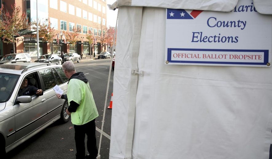 Doug Leaf, a ballot box security guard, grabs ballots from voters at the drive-up drop box in Salem, Ore., on Election Day, Tuesday, Nov. 6, 2018. (Anna Reed/Statesman-Journal via AP)