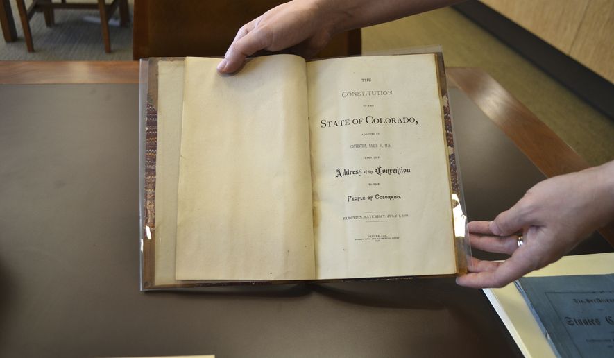 In this Nov. 12, 2016 photo, reference librarian Sarah Gilmor holds an 1876 copy of the Colorado Constitution which contains an exception under which slavery could be used as punishment for a crime, at the Stephen H. Hart Library & Research Center in Denver. Colorados voters were asked to eliminate an archaic and offensive reference to slavery as a punishment for a crime in the state Constitution. But a week after the vote, the poorly-written amendment is on the cusp of failing, and a lack of clarity from lawmakers may be to blame. (AP Photo/P. Solomon Banda)