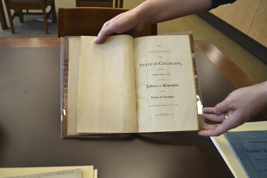 In this Nov. 12, 2016 photo, reference librarian Sarah Gilmor holds an 1876 copy of the Colorado Constitution which contains an exception under which slavery could be used as punishment for a crime, at the Stephen H. Hart Library & Research Center in Denver. Colorados voters were asked to eliminate an archaic and offensive reference to slavery as a punishment for a crime in the state Constitution. But a week after the vote, the poorly-written amendment is on the cusp of failing, and a lack of clarity from lawmakers may be to blame. (AP Photo/P. Solomon Banda)