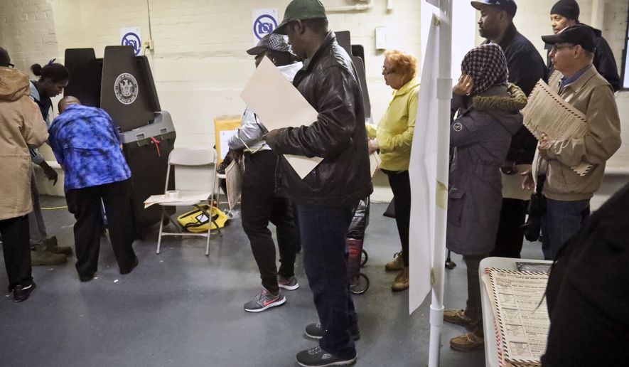 Polling site officials, left, check on a voting scanner after it jammed Tuesday, Nov. 6, 2018, in the Parkchester community of the Bronx borough of New York. The jam forced voters to manually file their ballots until a repair was made. (AP Photo/Bebeto Matthews)