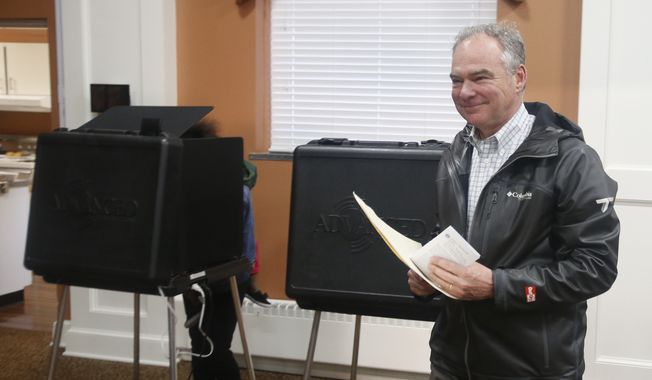 Sen. Tim Kaine, D-Va., carries his ballot to the vote counting machine as he votes in Richmond, Va., Tuesday, Nov. 6, 2018. Kaine is running against Republican Corey Stewart. (AP Photo/Steve Helber)