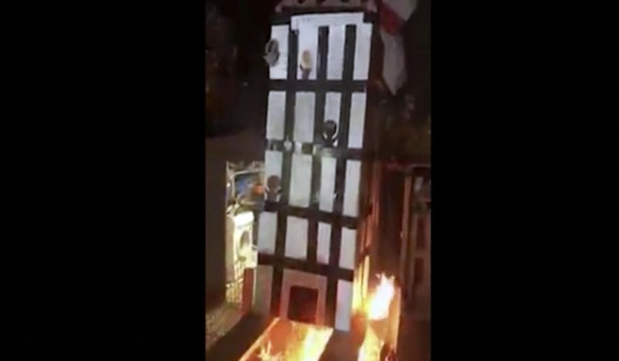 In this grab taken from video, made available on Tuesday, Nov. 6, 2018, people place a model of Grenfell Towers onto a bonfire, in London. London police have arrested five people over a video that showed a cardboard model of Grenfell Tower being burned on a bonfire — a video that shocked the families of the 72 victims who died in the 2017 inferno that engulfed the apartment block. (UGC via AP)