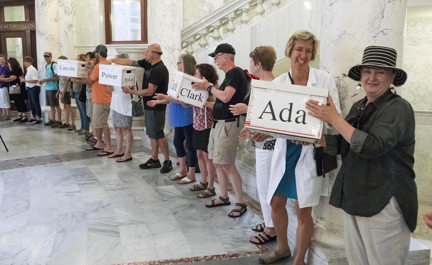 FILE--In this July 6, 2018, file photo, Dr. Kathleen Romito, M.D. hands a box full of signatures from Ada County to Kelly Goughnour, both of Boise, Idaho, at the Idaho Statehouse in Boise, Idaho. In a bucket-brigade-style delivery of more than 70,000 voter petitions from 44 counties, Idahoans For Healthcare volunteers delivered signatures to the Idaho Secretary of State calling for placement of a Medicaid expansion initiative the ballot. Voters will decide Proposition 2's fate Tuesday, Nov. 6, 2018. (Darin Oswald/Idaho Statesman via AP, file)