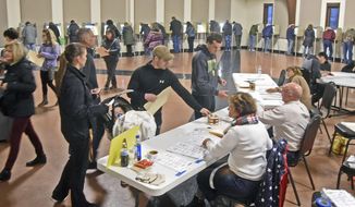 Voters line up to receive ballots while others fill voting booths inside the northwest Bismarck polling place in Century Baptist Church on Tuesday evening. (Tom Stromme/The Bismarck Tribune via AP)