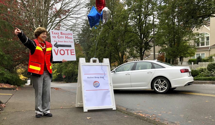 Elections volunteer Linda Brown points a voter to a designated ballot drop box in Lake Oswego, Oregon outside City Hall on Tuesday, Nov. 6, 2018. Brown said the dropbox location had been so busy that it was overflowing when elections workers emptied it Tuesday morning. Oregon is a vote-by-mail state and voters who have not mailed their ballots back by Election Day must deposit them in ballot boxes like this one. (AP Photo/Gillian Flaccus)