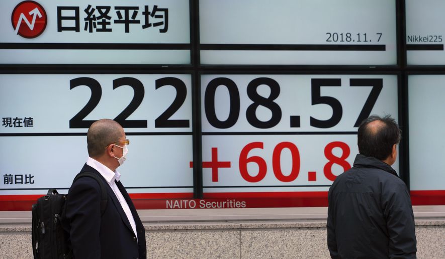 Men look at an electronic stock board showing Japan's Nikkei 225 index at a securities firm in Tokyo Wednesday, Nov. 7, 2018. Asian shares were mostly higher Wednesday as investors awaited results from the U.S. midterm elections, which could have an impact on the global economy and trade. (AP Photo/Eugene Hoshiko)