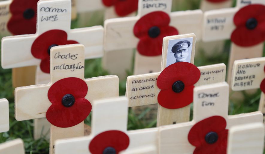 A rain drop covered photograph of Canadian soldier Fredrick George Coppins adorns a cross placed in the Field of Remembrance at Westminster Abbey in preparation for the annual Armistice Day commemoration for the dead and injured military and civilian in conflicts around the world on Nov. 11, in London, Wednesday, Nov. 7, 2018. (AP Photo/Alastair Grant)