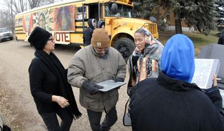 In this Tuesday, Nov. 6, 2018, photo Judith LeBlanc, left, with Four Directions, a non-profit voting equality organization for Native Americans, helps local volunteers Jeff McLaughlin, middle, and Susan Bears Heart before going door-to-door looking for voters in Selfridge, N.D., and offering a free bus ride to the polling precinct. Recent changes to North Dakota’s voter identification requirements that some believe were aimed at suppressing the Native American vote didn’t cause widespread problems Election Day. Advocacy groups credit an intense effort to ensure a strong Native vote that included free qualifying IDs and free rides to the polls. (Mike McCleary/The Bismarck Tribune via AP)
