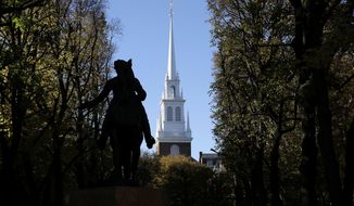 In this Wednesday, Nov. 7, 2018 photo Old North Church stands behind a statue of Paul Revere in the North End neighborhood of Boston. A bronze wreath and plaque that forms part of a memorial, which includes thousands of dog tags honoring soldiers killed in Iraq and Afghanistan, has been installed on the grounds of the church. The new plaque and wreath help explain the meaning of the dog tags and acknowledge Britain&#39;s contribution and sacrifice. (AP Photo/Steven Senne)