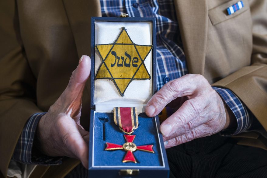 In this Nov. 5, 2018, photo Walter Frankenstein, born in 1924, witness of the Nov. 9, 1938 terror against Jews in Berlin and one of the few survivors of Auerbach&#x27;sches Waisenhaus orphanage shows a box with the Yellow badge the Nazis forced him to wear and with the Germany&#x27;s Federal Cross of Merit he got 2014, during an interview with The Associated Press in Berlin. Frankenstein witnessed as the orphanage was attack by a Nazis during the terror night of Nov. 9, 1938. (AP Photo/Markus Schreiber)