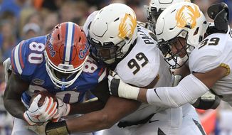 Florida tight end C&#39;yontai Lewis (80) is stopped for a loss by Missouri defensive linemen Walter Palmore (99) and Chris Turner (39) after catching a pass during the second half of an NCAA college football game Saturday, Nov. 3, 2018, in Gainesville, Fla. (AP Photo/Phelan M. Ebenhack)