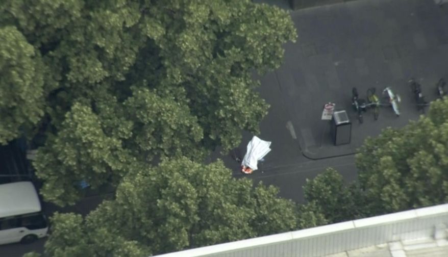 This image made from video shows white sheet covering object on street in Melbourne, Australia, Friday, Nov. 9, 2018. Police shot a knife-wielding man Friday after he fatally stabbed one person and injured two others in the center of Australia's second-largest city, police said. (Australian Broadcasting Corporation via AP)