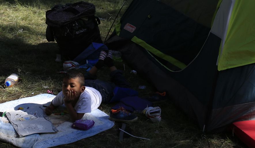 A boy lies with a coloring book outside a tent inside the sports complex where thousands of migrants have been camped out for several days in Mexico City, Friday, Nov. 9, 2018. About 500 Central American migrants headed out of Mexico City on Friday to embark on the longest and most dangerous leg of their journey to the U.S. border, while thousands more were waiting one day more at a massive improvised shelter.(AP Photo/Rebecca Blackwell)