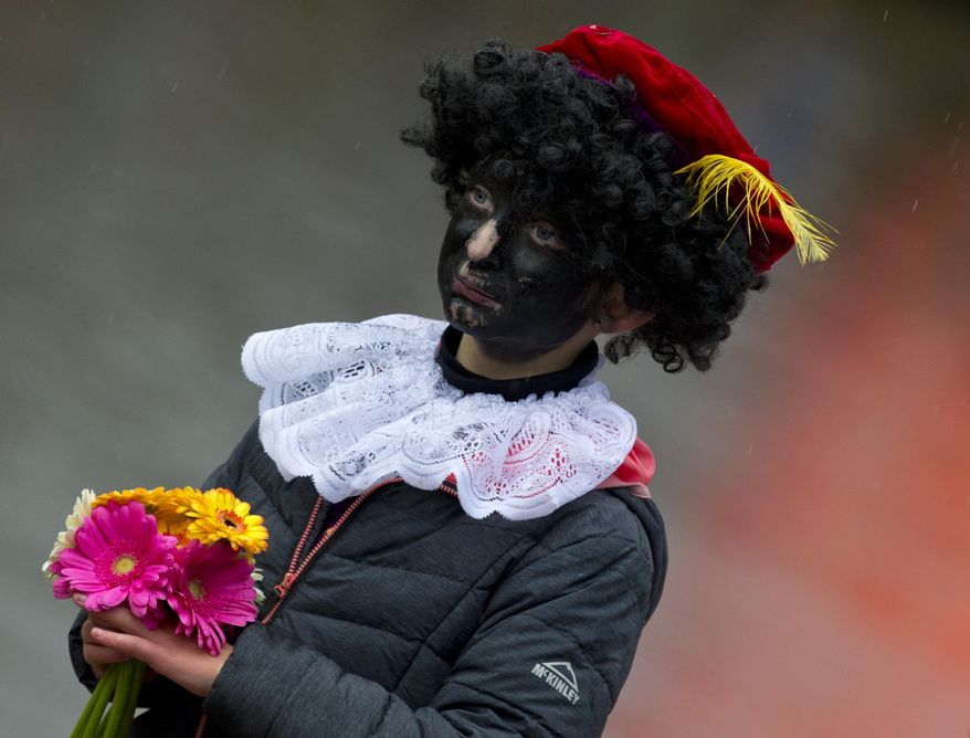 In this Saturday, Nov. 18, 2017, file photo, a child dressed as Black Pete waits for the arrival of Sinterklaas, in Dokkum, northern Netherlands. A court in the Netherlands has convicted 34 people on Friday NOv. 9, 2018, who blocked a highway last year to prevent anti-racism demonstrators reaching the nationally televised arrival of Sinterklaas, the Dutch version of Santa Claus, and his helpers called "Zwarte Piet", or Black Petes. Black Pete is often played by white people with their faces daubed in dark makeup. (AP Photo/Peter Dejong)