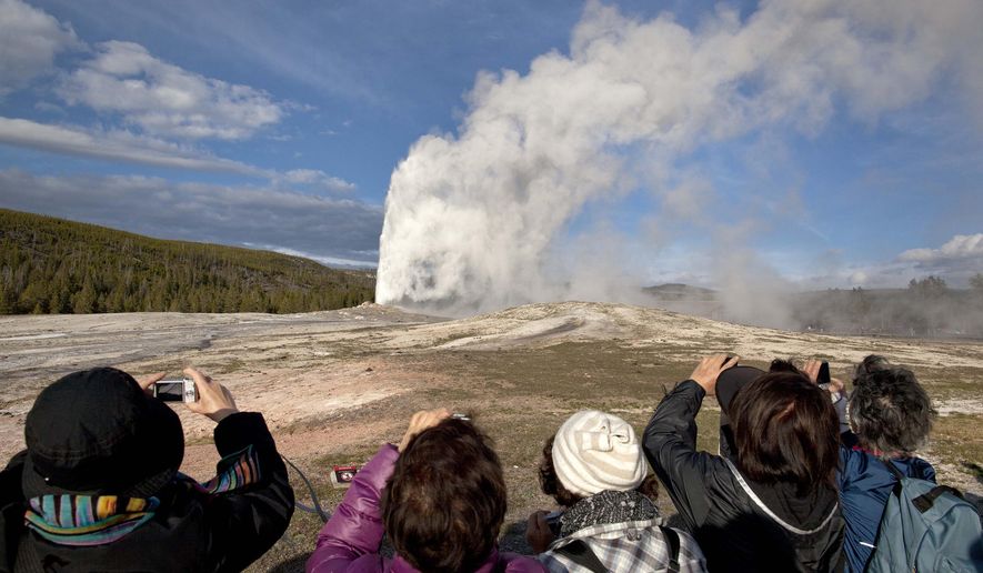 In this May 21, 2011, file photo, tourists photograph Old Faithful erupting on schedule late in the afternoon in Yellowstone National Park, Wyo. (AP Photo/Julie Jacobson, File)
