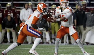 Clemson quarterback Trevor Lawrence, right, hands off to running back Travis Etienne during the first half of an NCAA college football game against Boston College, Saturday, Nov. 10, 2018, in Boston. (AP Photo/Elise Amendola)