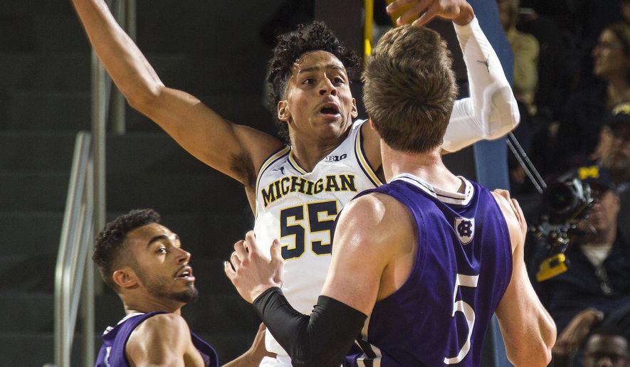 Michigan guard Eli Brooks (55) tries to intercept a pass from Holy Cross forward Connor Niego (5) to guard Kyle Copeland, left, during the first half of an NCAA college basketball game in Ann Arbor, Mich., Saturday, Nov. 10, 2018. (AP Photo/Tony Ding)