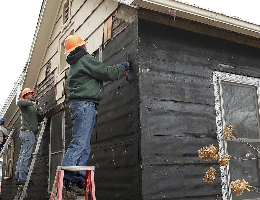 In this Nov. 8, 2018 photo, Ben Pfiffner, left, and Tom Hundt remove old siding on a Habitat for Humanity home in La Crosse Wis., as part of the Habitat for Heros program. Pfiffner is a veteran of the Air Force and Hundt is an Army vet. (Erik Daily/La Crosse Tribune via AP)