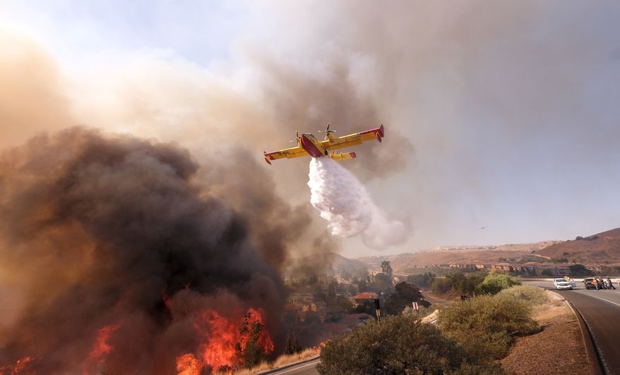 An air tanker drops water on a fire along the Ronald Reagan (118) Freeway in Simi Valley, Calif., Monday, Nov. 12, 2018. (AP Photo/Ringo H.W. Chiu)