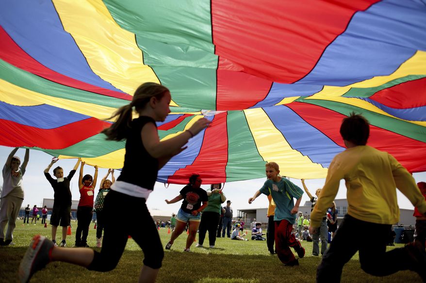 FILE - In this Thursday, April 25, 2013 file photo, elementary school third graders run under a rainbow colored tarp during the 15th Annual Kansas Kids Fitness Day, in Hutchinson, Kan. New federal guidelines released on Monday, Nov. 12, 2018, advise that children as young as age 3 should move more, sit less and get more active, and that any amount and any type of exercise helps health. (Aaron Marineau/The Hutchinson News via AP)