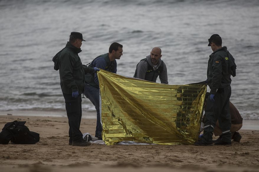 Members of the Spanish Civil Guard inspect the body of a dead migrant found on the beach at the village of Canos de Meca, where seventeen bodies were recovered from the sea after their precarious vessel impacted rocks while trying to reach Spanish coasts in the past week, Barbate, Spain, Monday, Nov. 12, 2018. (AP Photo/Javier Fergo)