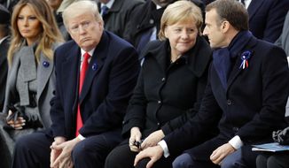U.S President Donald Trump, second left, watches French President Emmanuel Macron putting his hand on German Chancellor Angela Merkel&#39;s knee during ceremonies at the Arc de Triomphe Sunday, Nov. 11, 2018 in Paris. Over 60 heads of state and government were taking part in a solemn ceremony at the Tomb of the Unknown Soldier, the mute and powerful symbol of sacrifice to the millions who died from 1914-18. (AP Photo/Francois Mori, Pool)