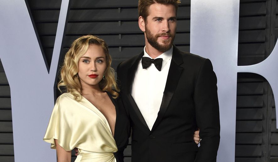 FILE - In this March 4, 2018 file photo, Miley Cyrus, left, and Liam Hemsworth arrive at the Vanity Fair Oscar Party in Beverly Hills, Calif. Though Cyrus and Hemsworth lost their home in the deadly wildfire blazing California, they are donating $500,000 to The Malibu Foundation through Cyrus’ charity, The Happy Hippie Foundation. (Photo by Evan Agostini/Invision/AP, FIle)