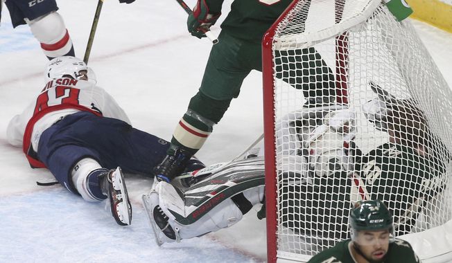 Washington Capitals&#x27; Tom Wilson, top left, looks back on his goal against Minnesota Wild goalie Devan Dubnyk, right, crashing into him in the first period of an NHL hockey game Tuesday, Nov. 13, 2018, in St. Paul, Minn. Wilson returned to the lineup after his 20-game suspension was reduced to 14 by a neutral arbitrator. After the goal Wilson received a two-minute penalty for goaltender interference. (AP Photo/Jim Mone)