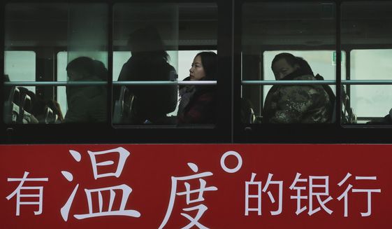 Commuters look out of a window of a bus with a bank advertise during the morning rush hour in Beijing, Tuesday, Nov. 13, 2018. The potential damage to global trade brought on by President Donald Trump&#39;s tariffs battle with Beijing is looming as leaders of Southeast Asian nations, China, the U.S. and other regional economies meet in Singapore this week. The advertisement reads &amp;quot;A warm-hearted bank.&amp;quot;  (AP Photo/Andy Wong)
