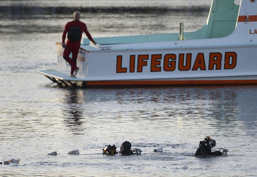 In this Thursday, April 9, 2015 photo, divers emerge from the water as debris believed to be from a car floats to the surface where a car went off the berth and into the water at the San Pedro Slip, across from Ports O'Call in San Pedro, Calif. U.S. prosecutors have charged an Egyptian father with fraudulently collecting insurance payouts after driving his family off a Los Angeles pier and killing his two severely autistic sons. Prosecutors said Tuesday, Nov. 13, 2018, that Ali Elmezayen had purchased $6 million in insurance policies to cover his family in the event of an accidental death two years before the 2015 deaths. (Steve McCrank/The Orange County Register via AP)