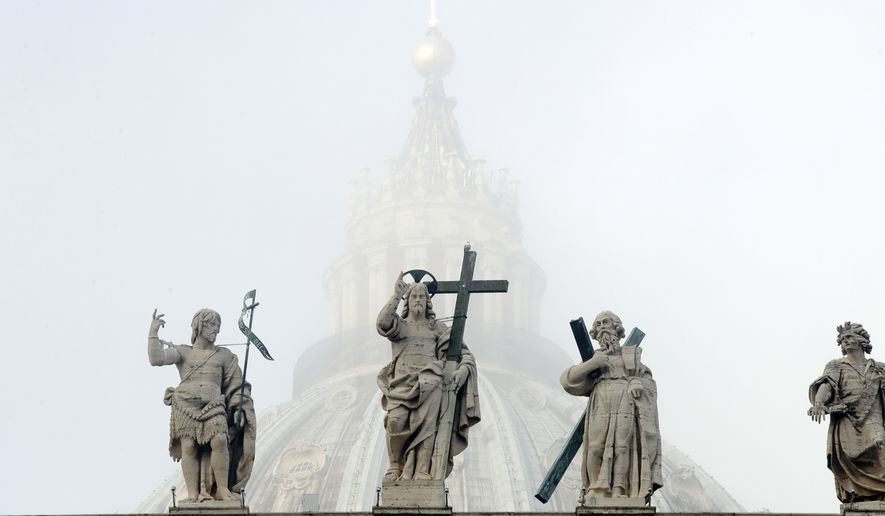 The dome of St. Peter's Basilica is partially engulfed in the fog behind statues of saints adorning the colonnade designed by 16th century Italian sculptor and architect Gian Lorenzo Bernini, in St. Peter's Square, at the Vatican, Wednesday, Nov. 14, 2018. (AP Photo/Andrew Medichini)