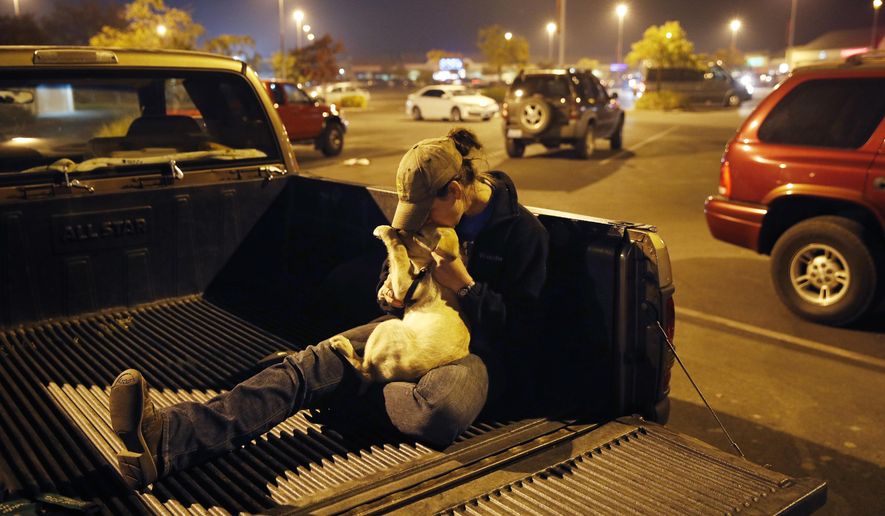 Sarah Gronseth kisses her dog Branch in the bed of a truck in a parking lot, Tuesday, Nov. 13, 2018, in Chico Calif. Gronseth, a teacher, evacuated some of her high school students in her truck as the fire bore down on the high school in Paradise, Calif. She lost her home in the fire. (AP Photo/John Locher)