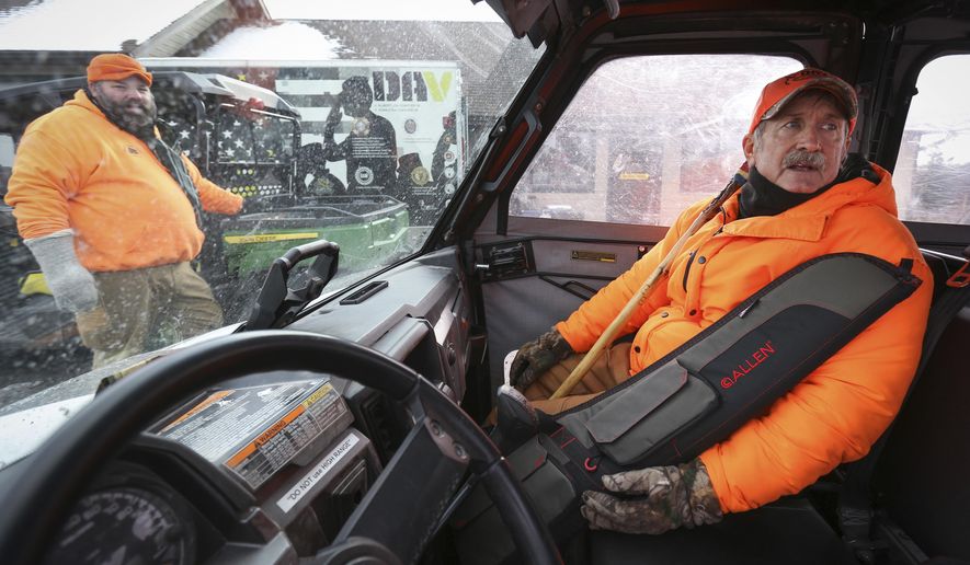 ADVANCE FOR USE MONDAY, NOV. 19 - In this Friday, Nov. 9, 2018 photo, veteran Tom McLaughlin, right, readies himself for a ride to a deer blind in Chester Woods Park in Olmsted County, Minn., with help from Nate Pike, left, of Olmsted County Veterans Services. Olmsted County has closed the park for about two weeks to allow hunts to manage the deer herd in the park. Disabled veterans get an opportunity to hunt for four of those days. (Ken Klotzbach/The Rochester Post-Bulletin via AP)