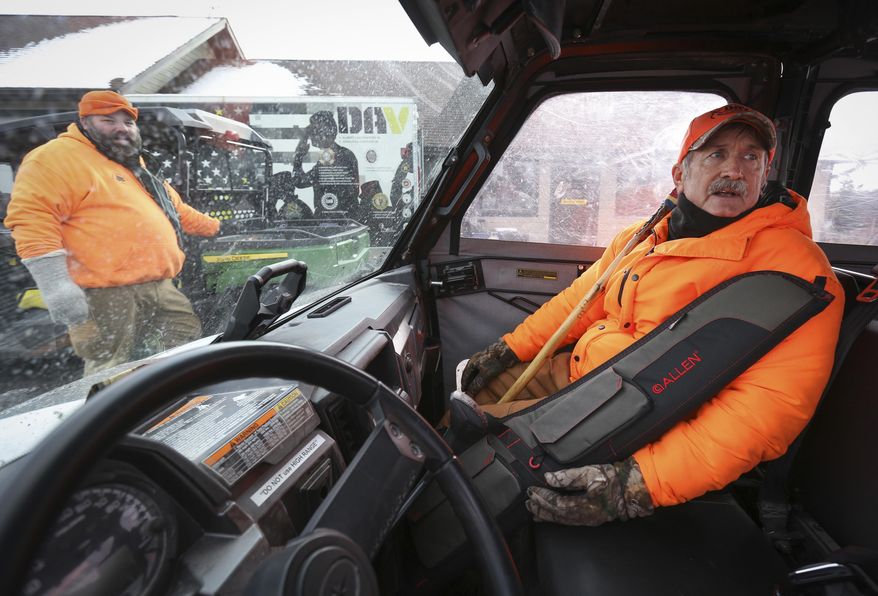 ADVANCE FOR USE MONDAY, NOV. 19 - In this Friday, Nov. 9, 2018 photo, veteran Tom McLaughlin, right, readies himself for a ride to a deer blind in Chester Woods Park in Olmsted County, Minn., with help from Nate Pike, left, of Olmsted County Veterans Services. Olmsted County has closed the park for about two weeks to allow hunts to manage the deer herd in the park. Disabled veterans get an opportunity to hunt for four of those days. (Ken Klotzbach/The Rochester Post-Bulletin via AP)