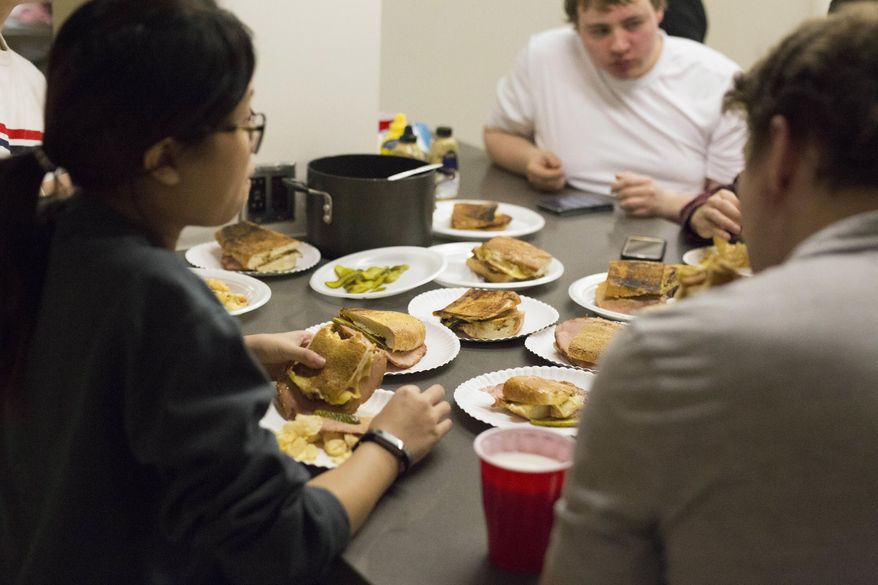 In this Wednesday, Nov. 7, 2018 photo, members of the University of Minnesota's Cooking Club gather outside the kitchen in Coffman Memorial Union to enjoy the meal they just prepared together in Minneapolis. A love of food, the social networking website Reddit and a persistent University of Minnesota graduate student, Justin Wiese, who wanted to create a space for people who like to eat were all factors in the creation of the university’s cooking club. (Jerusa Nyakundi/The Minnesota Daily via AP)