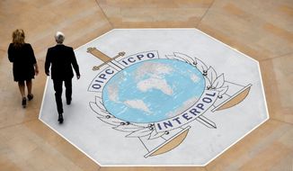 In this photo taken on Thursday, Nov.8, 2018 people walk on the Interpol logo at the international police agency headquarters in Lyon, central France. (AP Photo/Laurent Cipriani)