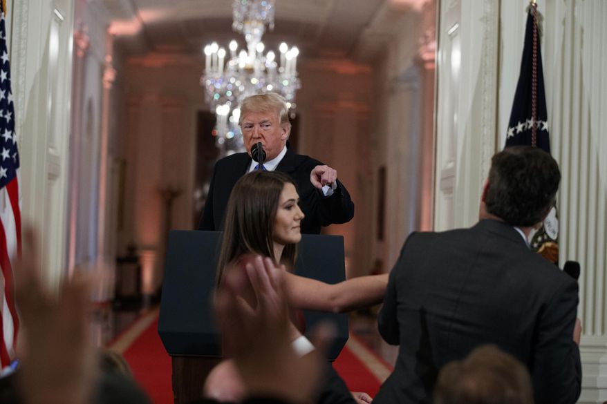 FILE - In this Nov. 7, 2018 file photo, President Donald Trump watches as a White House aide reaches to take away a microphone from CNN journalist Jim Acosta during a news conference in the East Room of the White House in Washington. CNN is suing the Trump administration, demanding that Acosta’s press credentials to cover the White House be returned. The administration revoked them last week following President Trump’s contentious news conference, where Acosta refused to give up a microphone when the president said he didn’t want to hear anything more from him. (AP Photo/Evan Vucci, File)