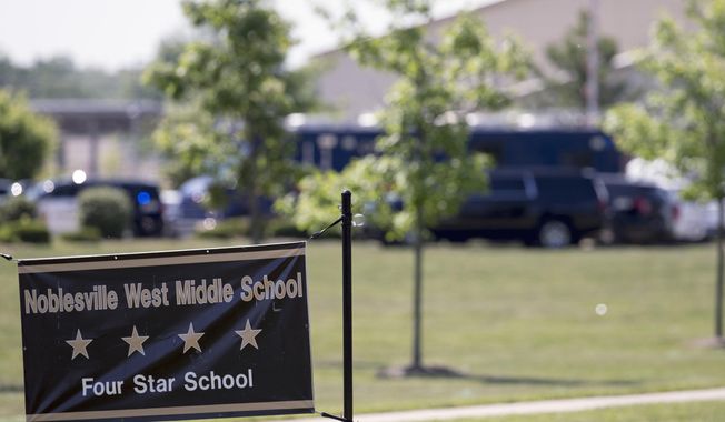 FILE - In this May 25, 2018, file photo, Law enforcement vehicles are seen behind a school sign after a shooting at Noblesville West Middle School in Noblesville, Ind. The 13-year-old boy who opened fire inside the school, wounding a classmate and a teacher before being tackled by the teacher, was expected to learn his punishment on Wednesday, Nov. 14, 2018. (Robert Scheer/The Indianapolis Star via AP, File)