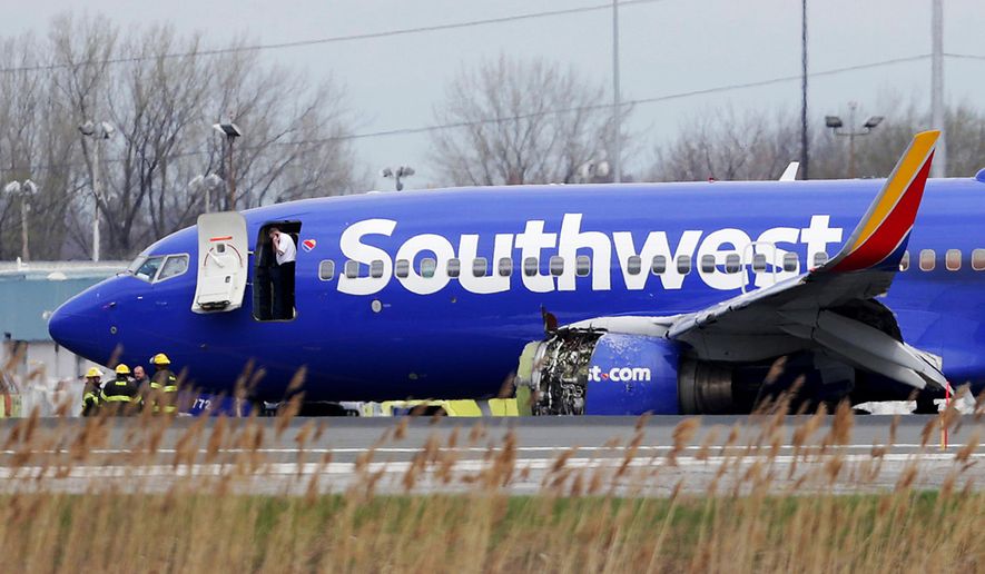 FILE- In this April 17, 2018, file photo a Southwest Airlines plane sits on the runway at the Philadelphia International Airport after it made an emergency landing in Philadelphia. In new accounts released Wednesday, Nov. 14, into the April accident, the flight attendants described being unable to bring the woman back in the plane until two male passengers stepped in to help. The flight attendants told investigators at least one of the men put his arm out of the window and wrapped it around the woman’s shoulder to help pull her back in. (David Maialetti/The Philadelphia Inquirer via AP)