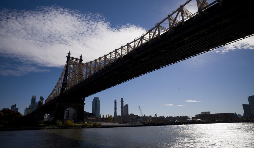 FILE- In this Wednesday, Nov. 7, 2018, file photo, the East River flows under the Ed Koch Queensboro Bridge and past the Long Island City skyline and waterfront in New York. On Tuesday, Nov. 13, Amazon said it will split its second headquarters between Long Island City in New York and Crystal City. An expansion of that scope in a major city such as New York may seem like something a transit system could absorb. But some fear the addition of more commuters on already overcrowded roads and trains will just add to commuters’ headaches where Amazon makes its new homes. (AP Photo/Mark Lennihan, File)