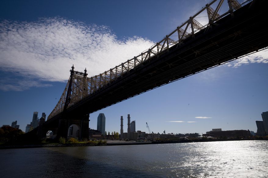 FILE- In this Wednesday, Nov. 7, 2018, file photo, the East River flows under the Ed Koch Queensboro Bridge and past the Long Island City skyline and waterfront in New York. On Tuesday, Nov. 13, Amazon said it will split its second headquarters between Long Island City in New York and Crystal City. An expansion of that scope in a major city such as New York may seem like something a transit system could absorb. But some fear the addition of more commuters on already overcrowded roads and trains will just add to commuters’ headaches where Amazon makes its new homes. (AP Photo/Mark Lennihan, File)