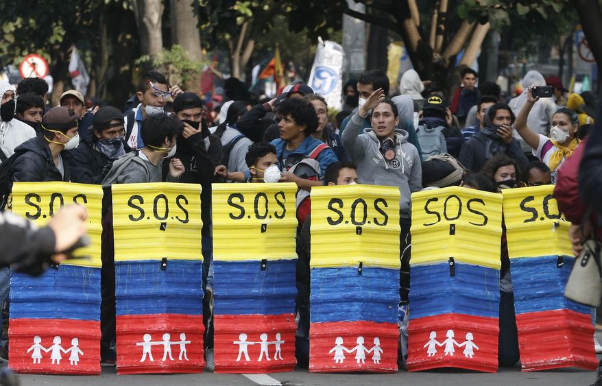 University students use homemade shields to cover themselves from the police during a protest asking for a hike in the budget for public higher education, in Bogota, Colombia, Thursday, Nov. 15, 2018. The so-called “Pencil March” is the latest in more than a half-dozen street protests in recent months demanding the government step up funding for education. (AP Photo/Fernando Vergara)